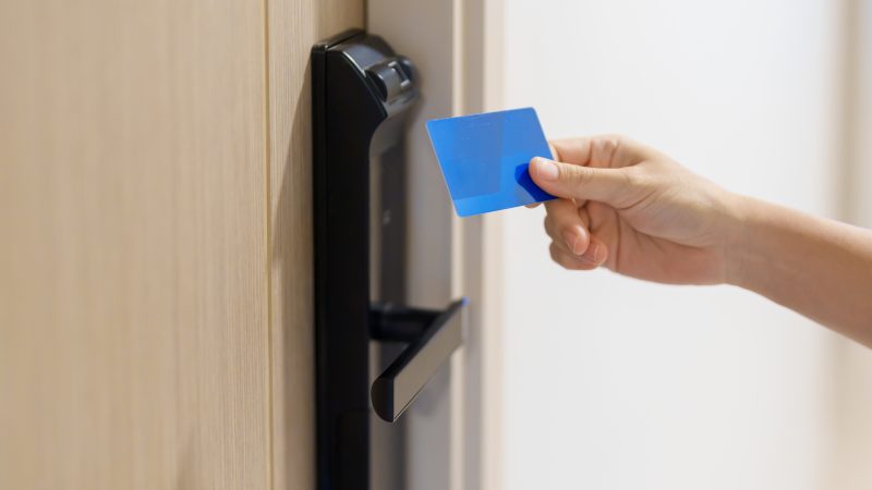 Hand using keycard for smart digital door lock while open