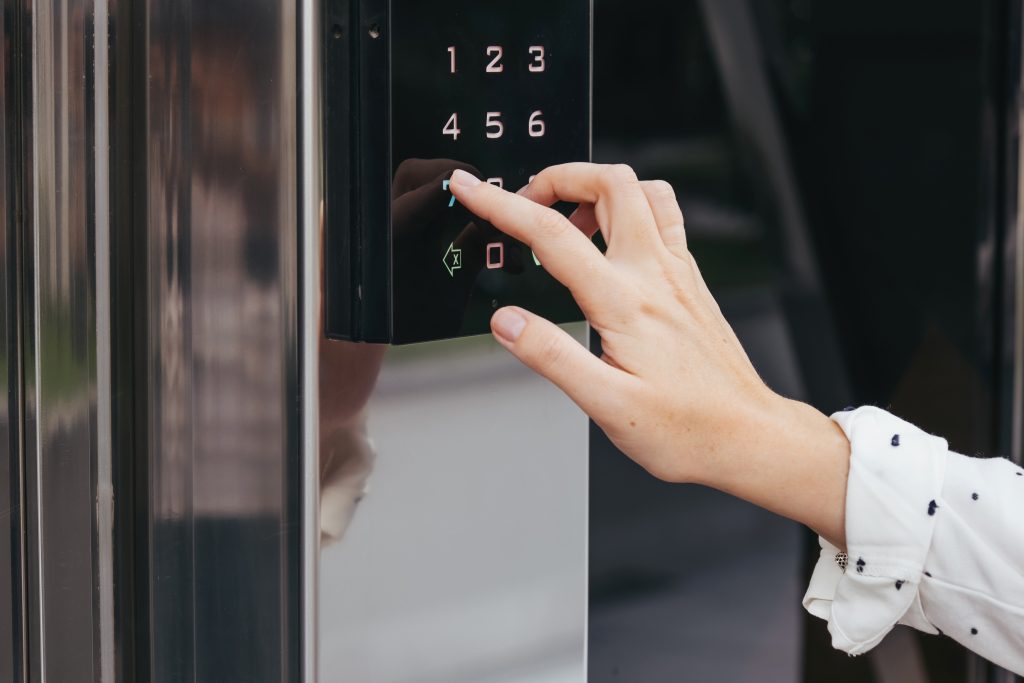 Woman's hand using an intercom at entrance to building. Using an electronic lock.